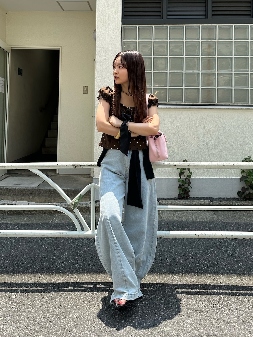 ブラウン系のTシャツ/カットソー、ブルー系のデニムパンツ、ピンク系のハンドバッグを着用したレディースの夏コーディネートの2枚目の写真