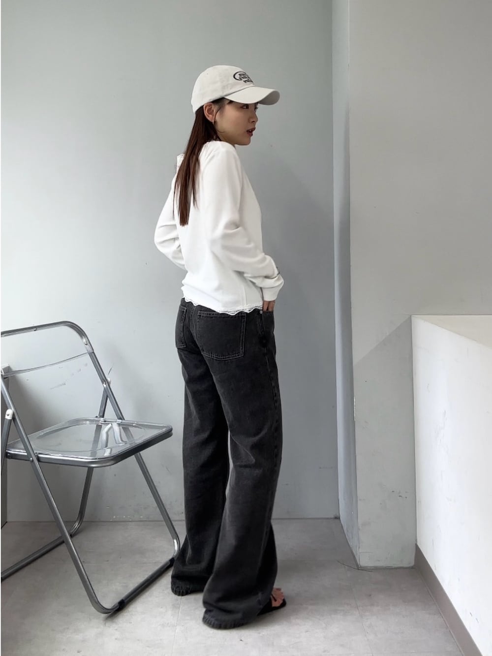 ブラック系のデニムパンツ、ホワイト系のTシャツ/カットソー、ブラック系のサンダルを着用したレディースの春コーディネートの2枚目の写真