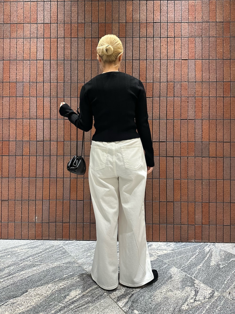 ブラック系のカーディガン/ボレロ、ホワイト系のデニムパンツ、ブラック系のショルダーバッグを着用したレディースの春コーディネートの4枚目の写真