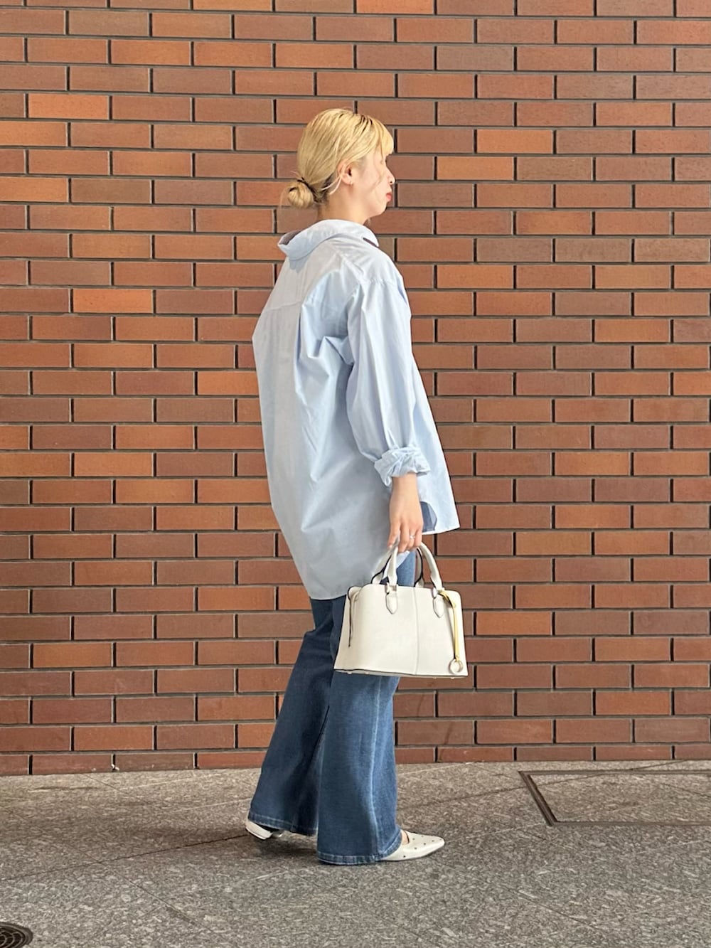 ブルー系のシャツ/ブラウス、ブルー系のデニムパンツ、ホワイト系のハンドバッグを着用したレディースの春コーディネートの2枚目の写真