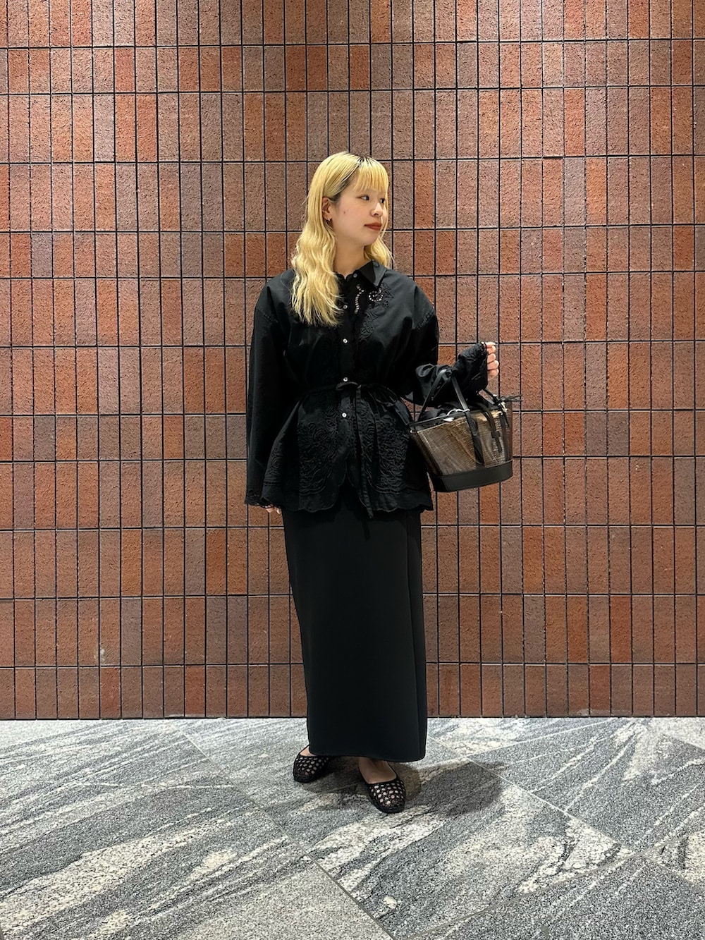 ブラック系のシャツ/ブラウス、ブラック系のサンダル、ブラック系のかごバッグを着用したレディースの春コーディネートの3枚目の写真