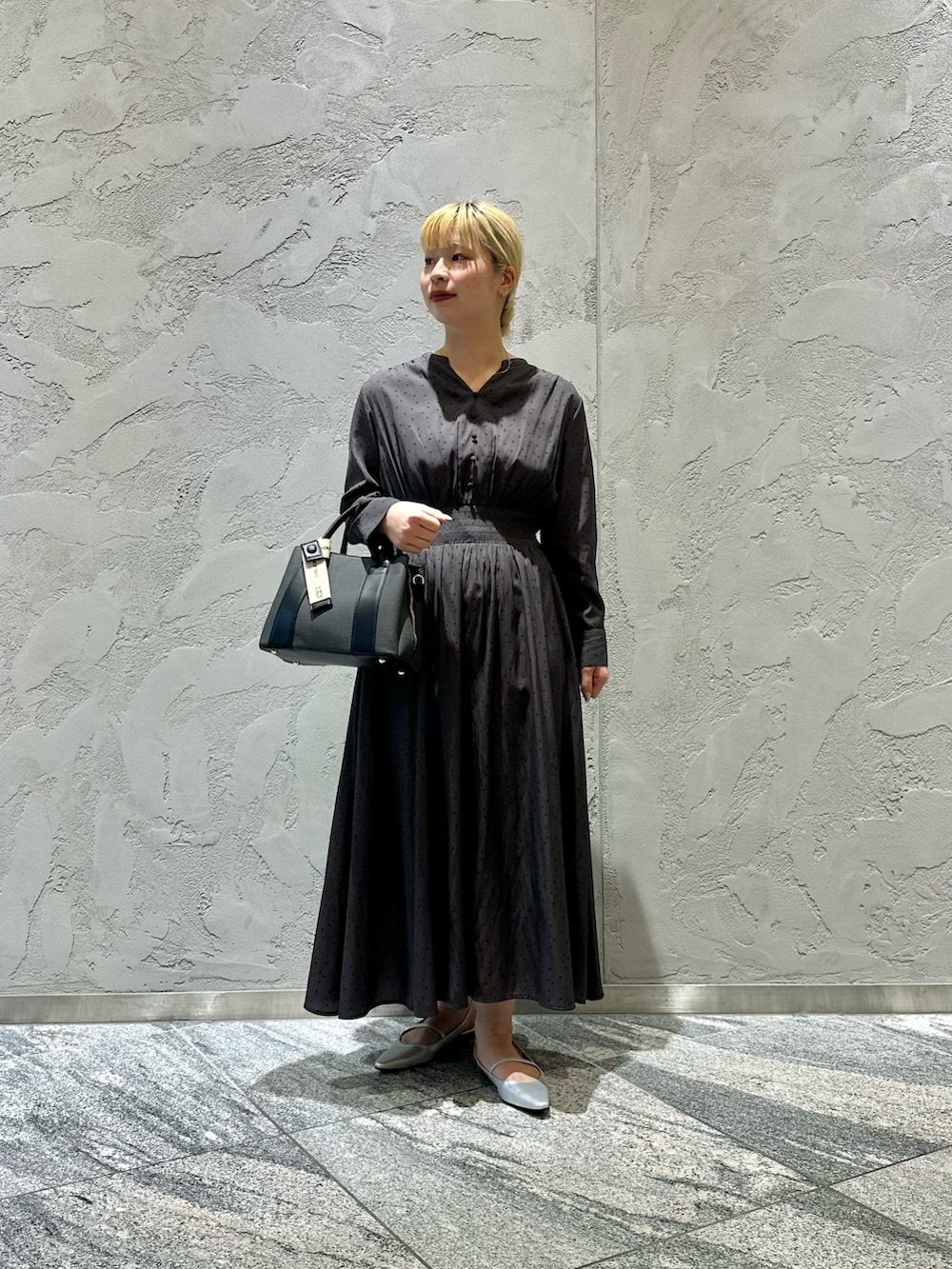 グレー系のワンピース、ブラック系のハンドバッグ、シルバー系のパンプスを着用したレディースの春コーディネートの5枚目の写真