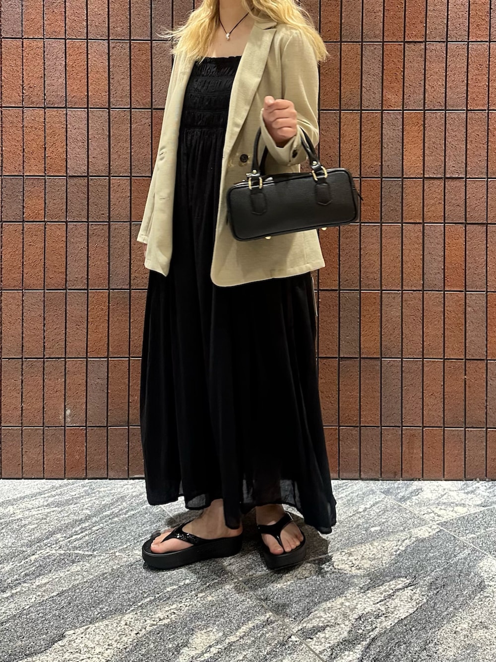 ブラック系のワンピース、ブラック系のハンドバッグ、ベージュ系のその他アウターを着用したレディースの春コーディネートの2枚目の写真