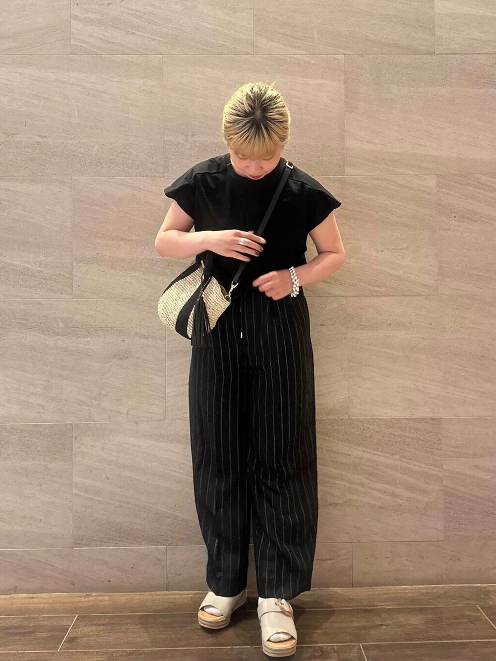 ベージュ系のかごバッグ、ブラック系のTシャツ/カットソー、ブラック系のその他パンツを着用したレディースの春コーディネートの2枚目の写真