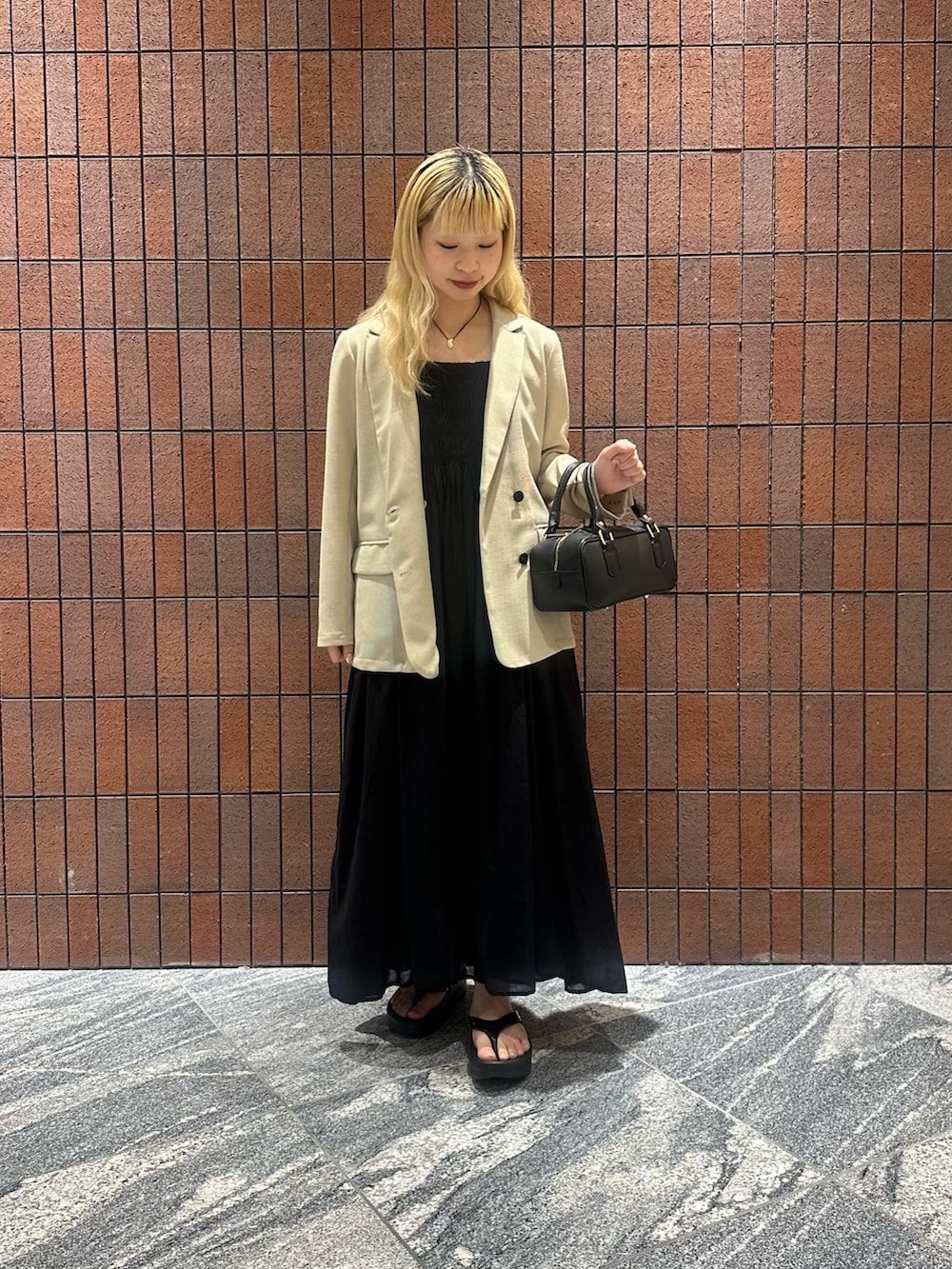 ブラック系のワンピース、ブラック系のハンドバッグ、ベージュ系のその他アウターを着用したレディースの春コーディネートの5枚目の写真
