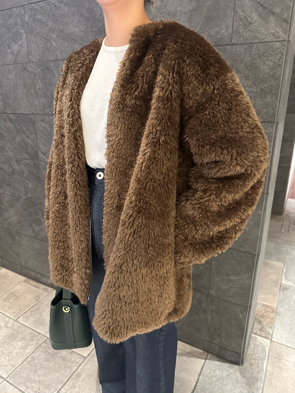 ブラウン系のノーカラージャケット、ホワイト系のTシャツ/カットソー、ブルー系のデニムパンツを着用したレディースの秋コーディネートの4枚目の写真