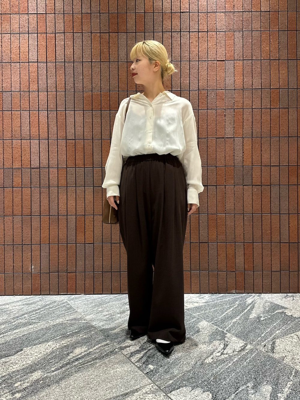 ホワイト系のシャツ/ブラウス、ブラック系のパンプス、ブラウン系のボストンバッグを着用したレディースの春コーディネートの2枚目の写真