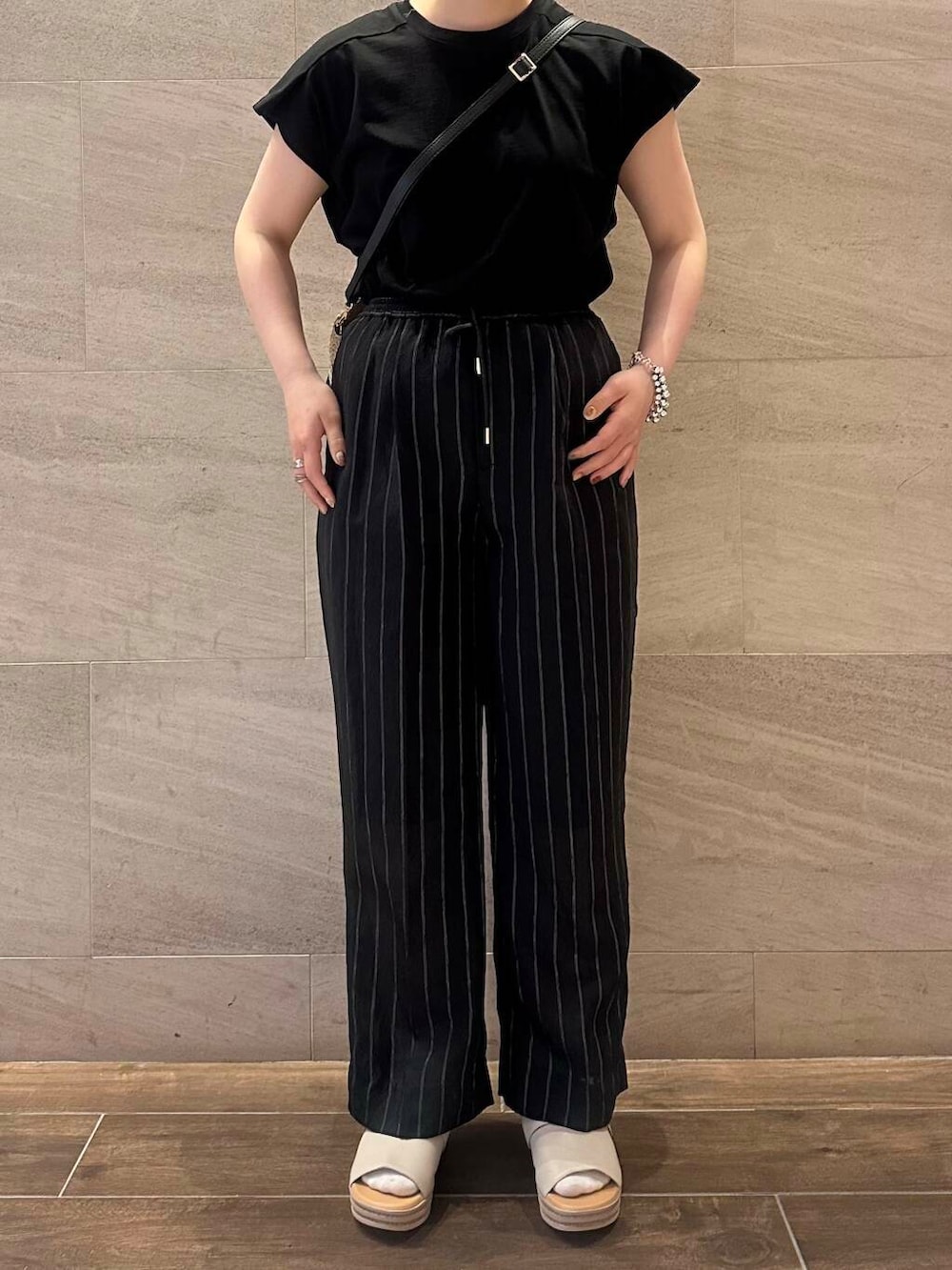 ベージュ系のかごバッグ、ブラック系のTシャツ/カットソー、ブラック系のその他パンツを着用したレディースの春コーディネートの3枚目の写真