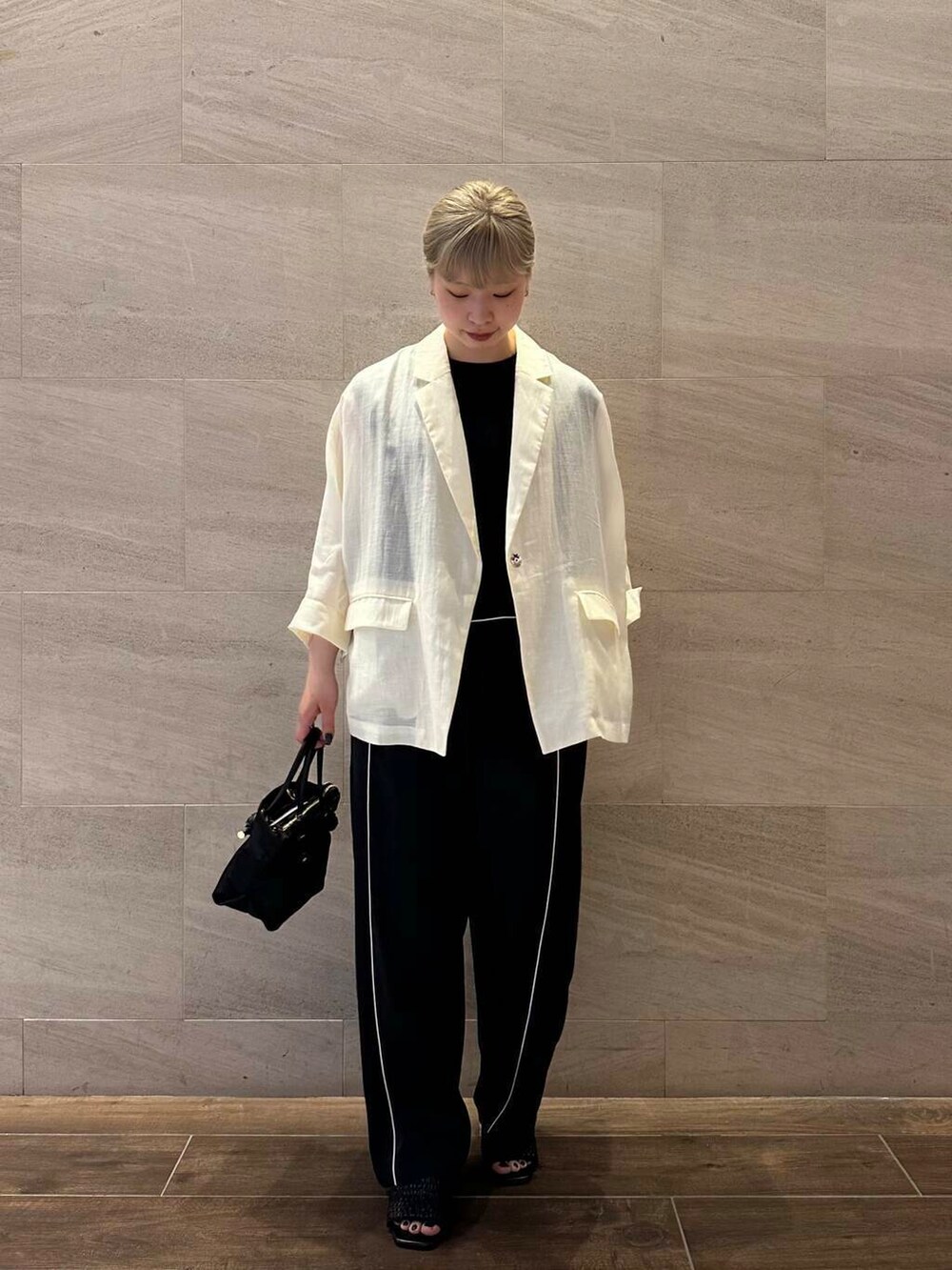 ブラック系のトートバッグ、ブラック系のニット/セーター、ホワイト系のその他アウターを着用したレディースの夏コーディネートの3枚目の写真