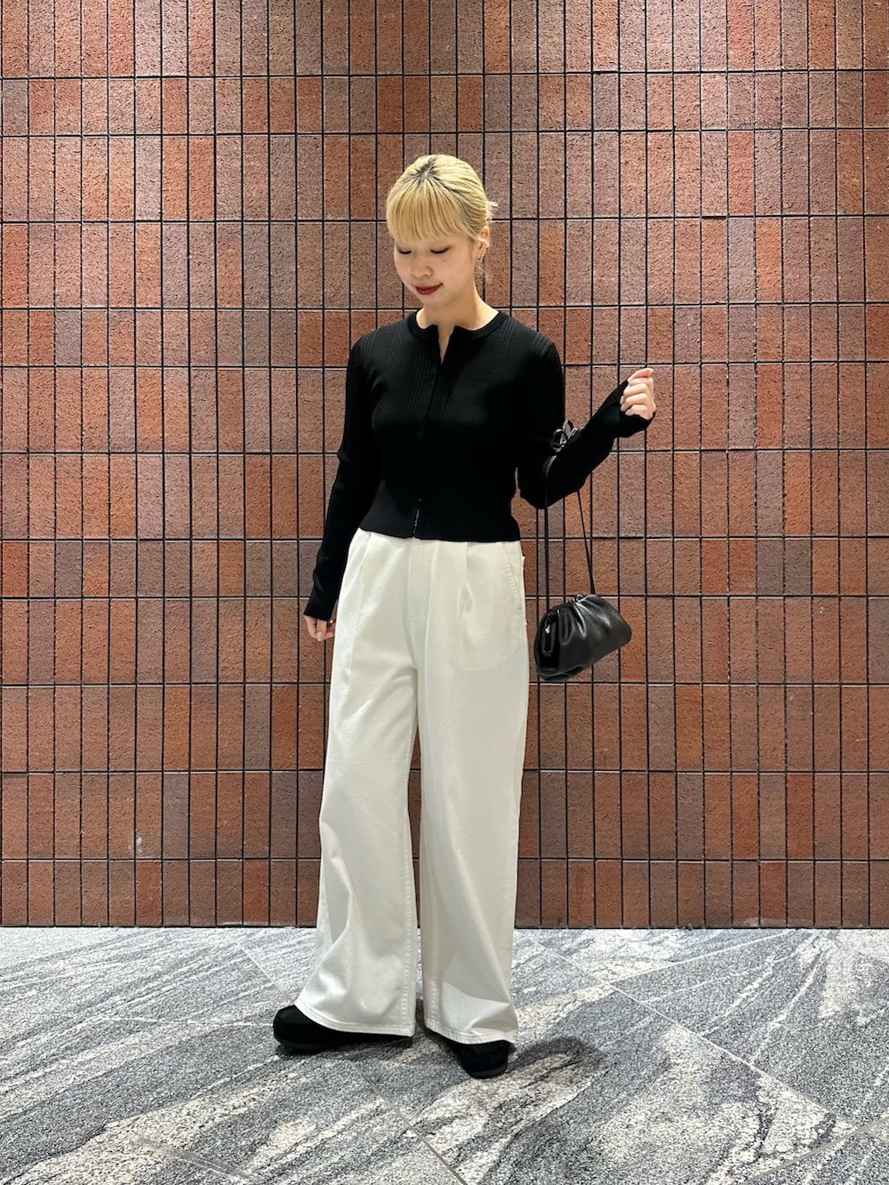 ブラック系のカーディガン/ボレロ、ホワイト系のデニムパンツ、ブラック系のショルダーバッグを着用したレディースの春コーディネートの2枚目の写真