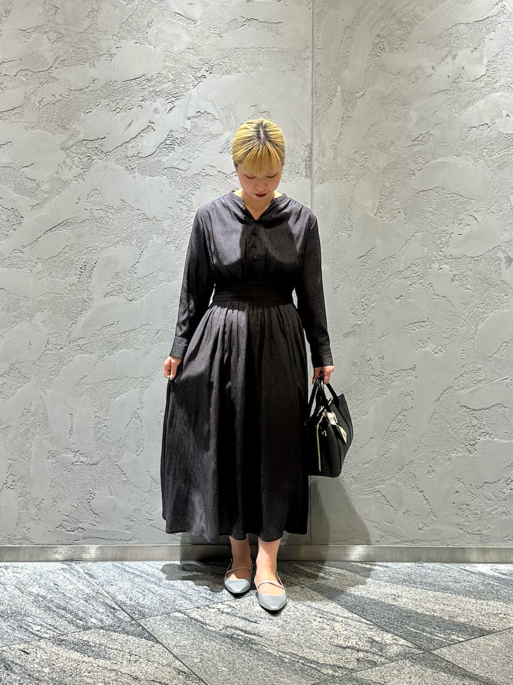 グレー系のワンピース、ブラック系のハンドバッグ、シルバー系のパンプスを着用したレディースの春コーディネートの3枚目の写真