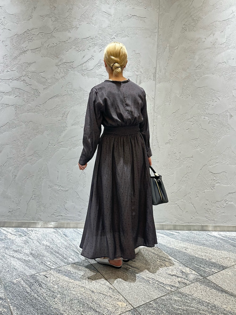 グレー系のワンピース、ブラック系のハンドバッグ、シルバー系のパンプスを着用したレディースの春コーディネートの4枚目の写真