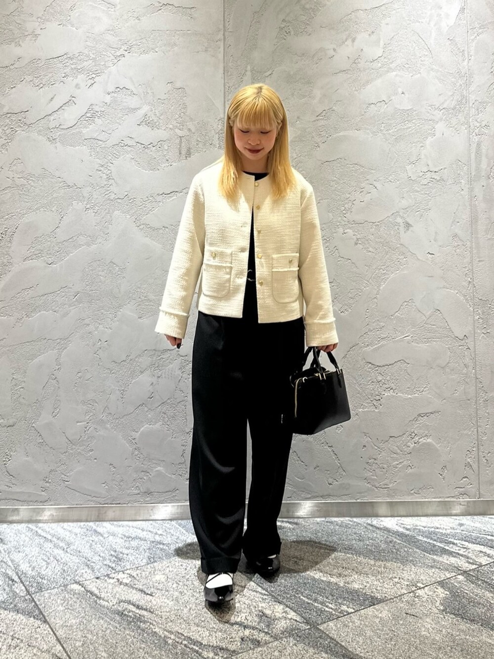 ホワイト系のノーカラージャケット、ブラック系のその他パンツ、ブラック系のハンドバッグを着用したレディースの冬コーディネートの4枚目の写真