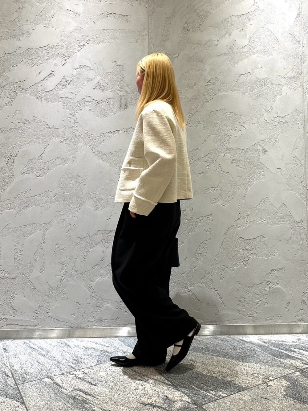 ホワイト系のノーカラージャケット、ブラック系のその他パンツ、ブラック系のハンドバッグを着用したレディースの冬コーディネートの2枚目の写真