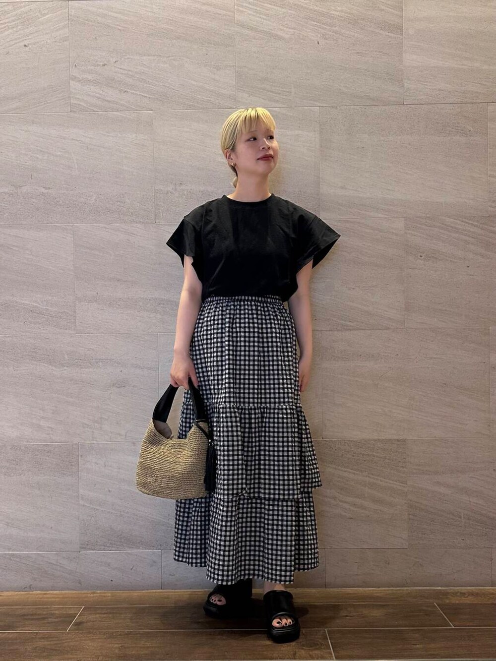 ブラウン系のかごバッグ、その他のスカート、ブラック系のTシャツ/カットソーを着用したレディースの夏コーディネートの2枚目の写真