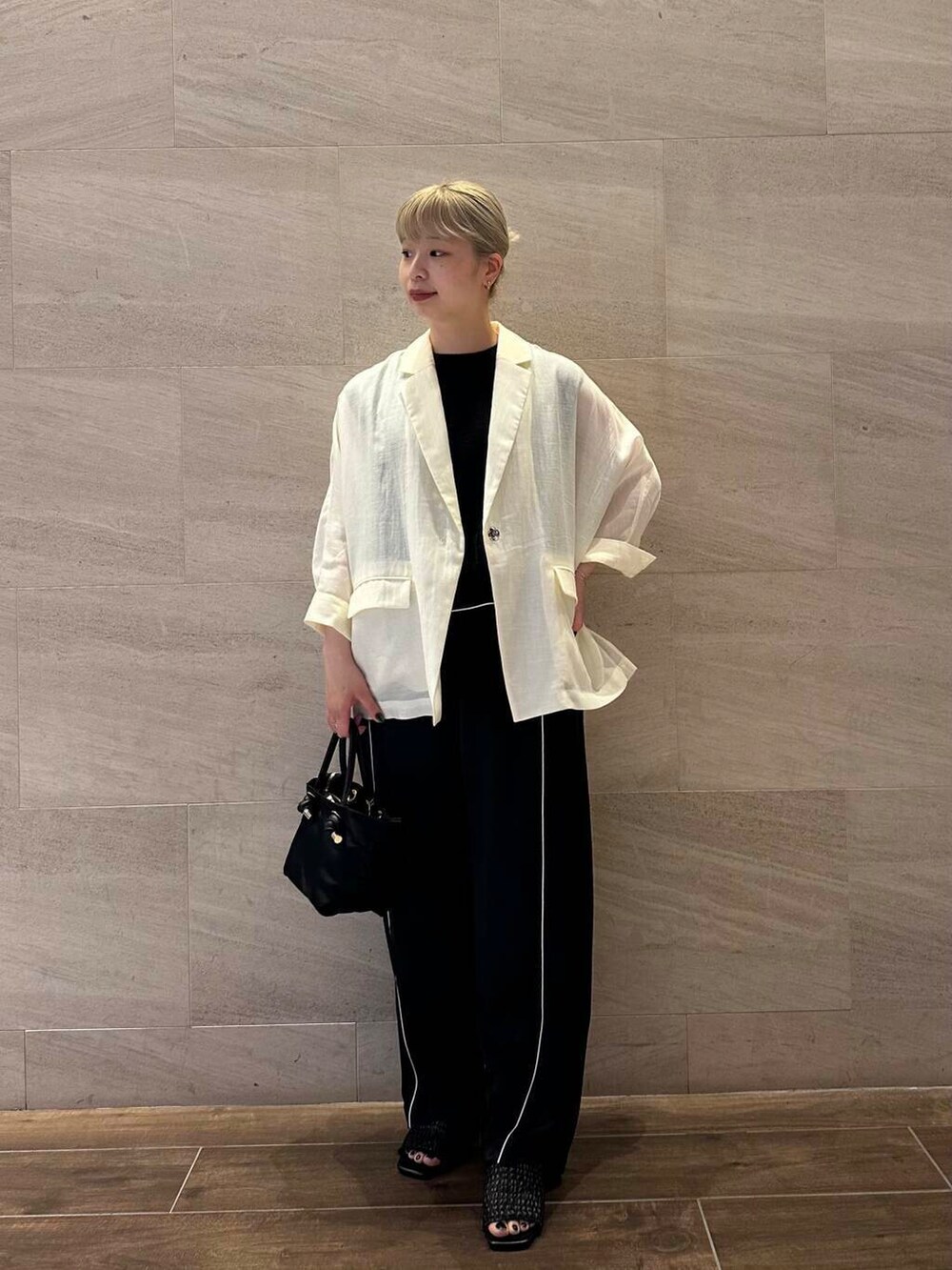 ブラック系のトートバッグ、ブラック系のニット/セーター、ホワイト系のその他アウターを着用したレディースの夏コーディネートの2枚目の写真