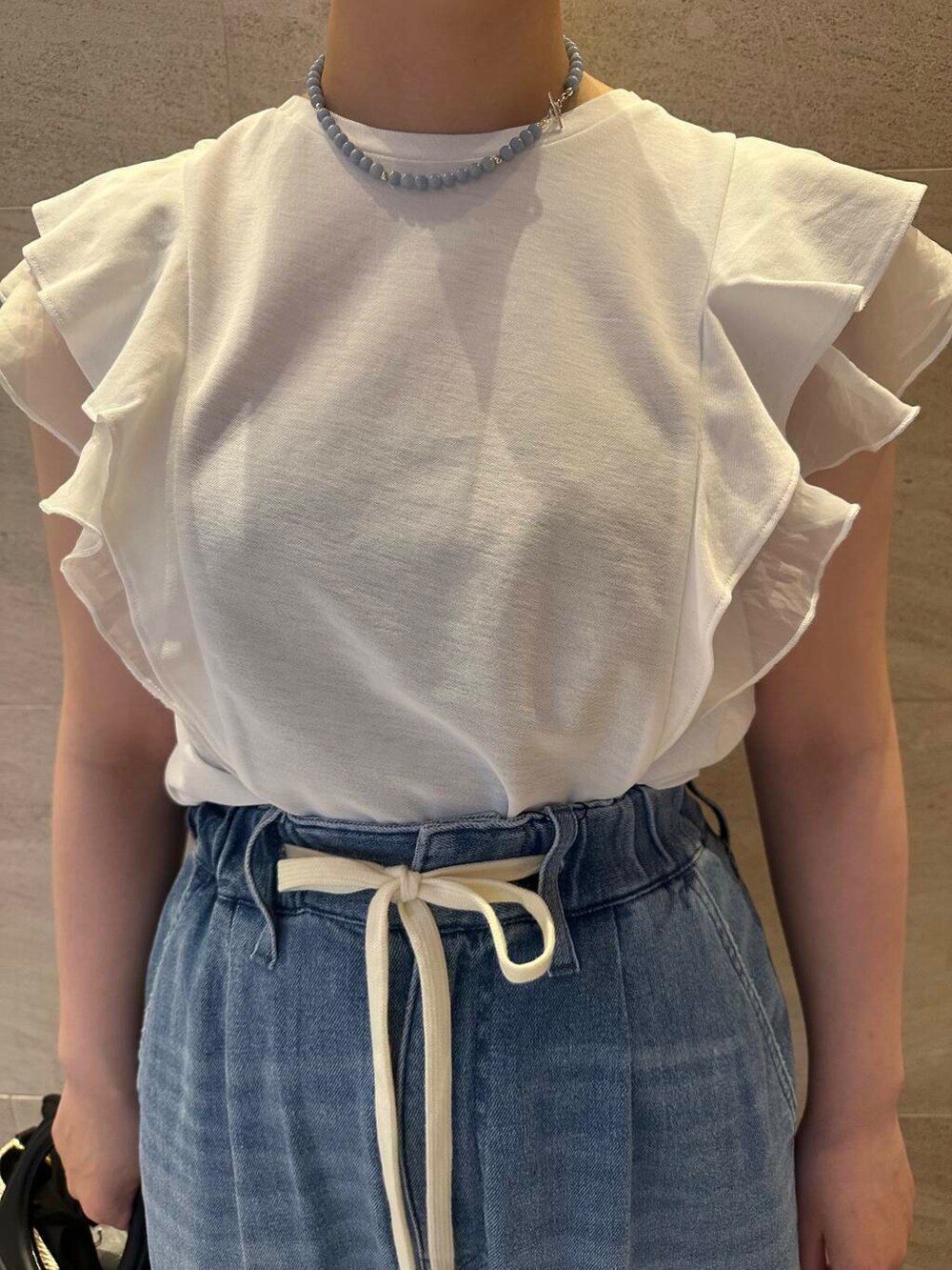 ベージュ系のショルダーバッグ、ブルー系のデニムパンツ、ホワイト系のTシャツ/カットソーを着用したレディースの夏コーディネートの4枚目の写真