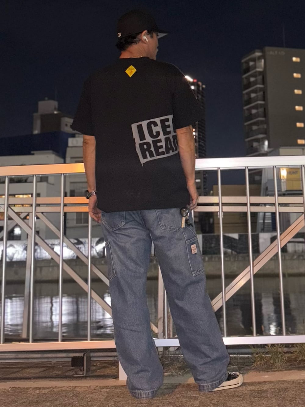 ブルー系のデニムパンツ、ブラック系のTシャツ/カットソー、ブラック系のスニーカーを着用したメンズの秋コーディネートの2枚目の写真