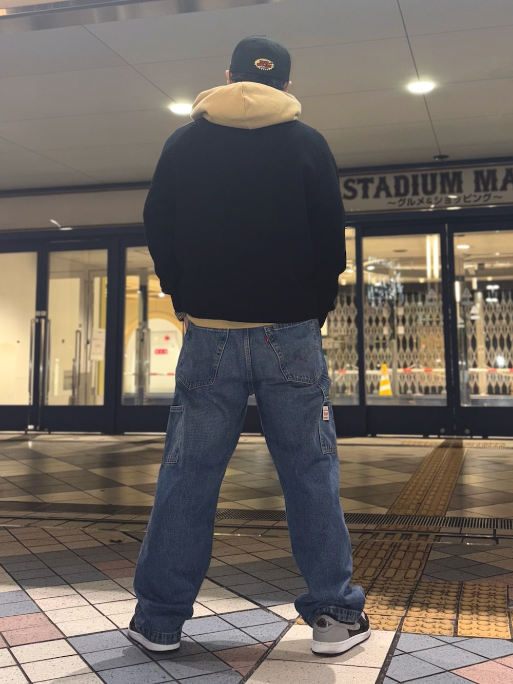 ブラック系のニット/セーター、イエロー系のパーカー、ブルー系のデニムパンツを着用したメンズの冬コーディネートの2枚目の写真