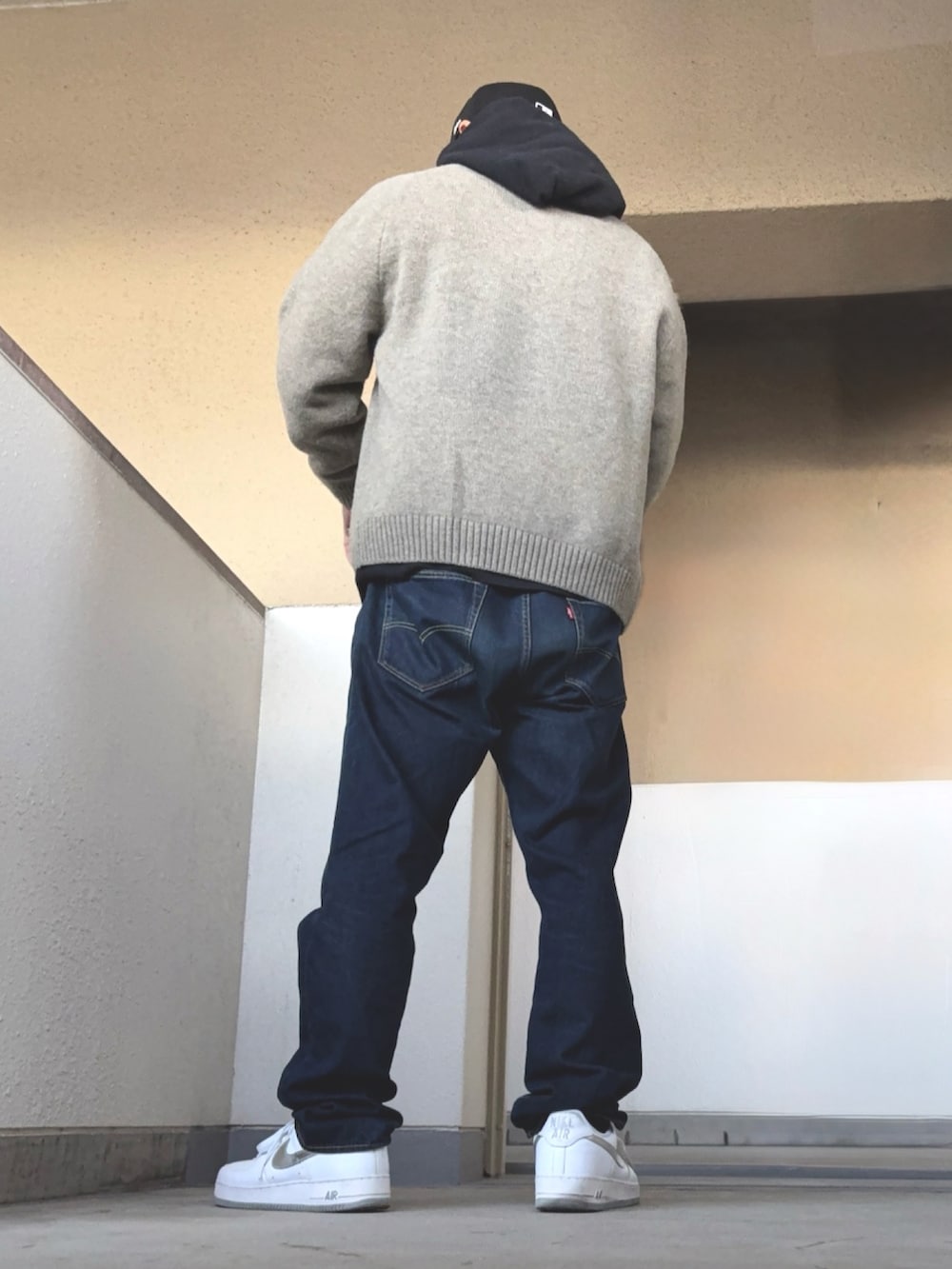 グレー系のニット/セーター、ブラック系のパーカー、ブルー系のデニムパンツを着用したメンズの冬コーディネートの3枚目の写真