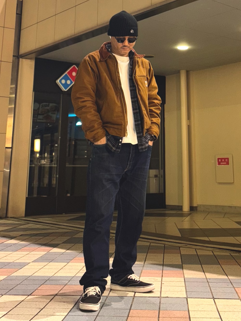 イエロー系のブルゾン、ブルー系のデニムパンツ、ブラック系のスニーカーを着用したメンズの冬コーディネートの2枚目の写真