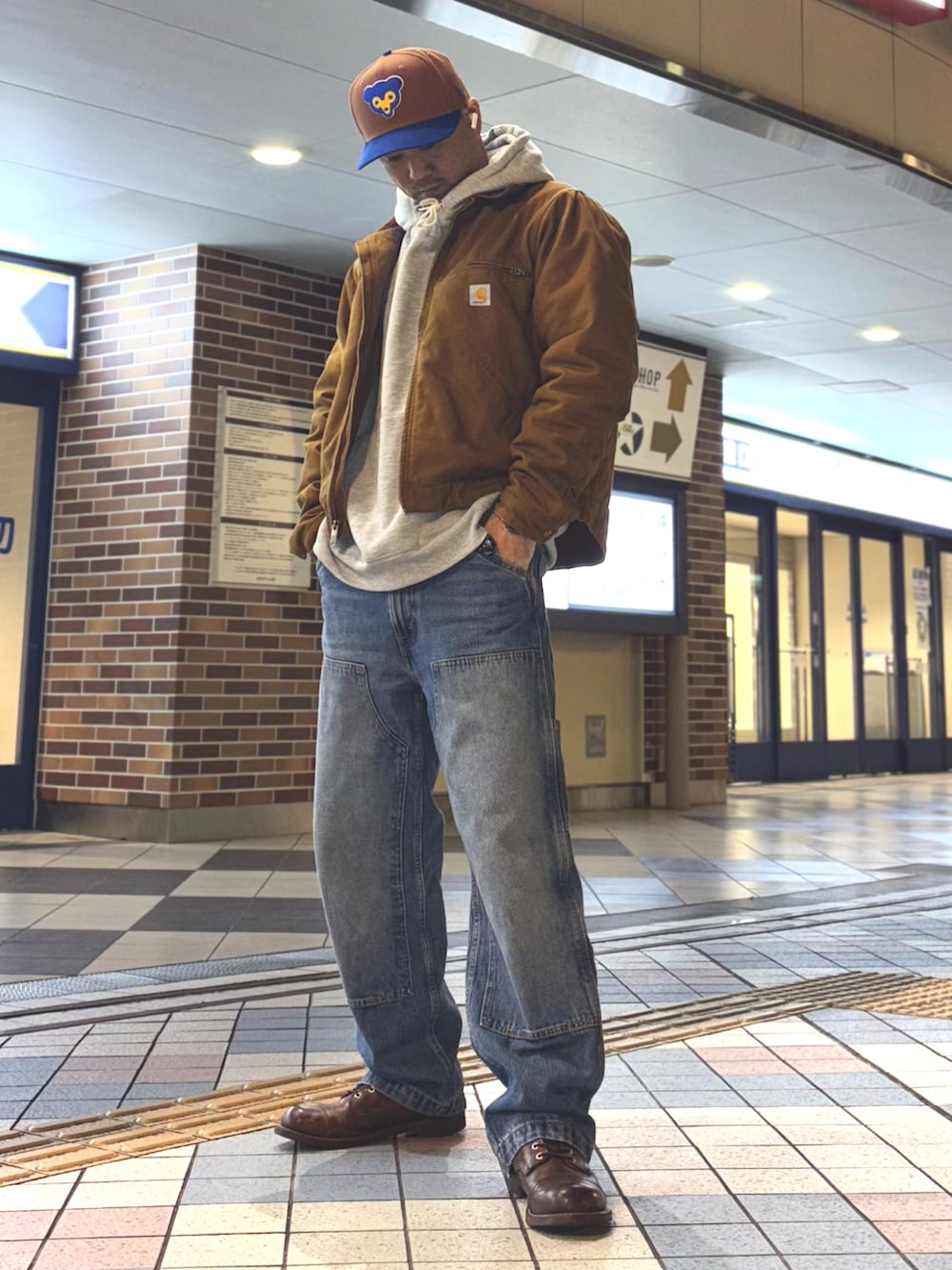 イエロー系のブルゾン、グレー系のパーカー、ブルー系のデニムパンツを着用したメンズの冬コーディネートの3枚目の写真