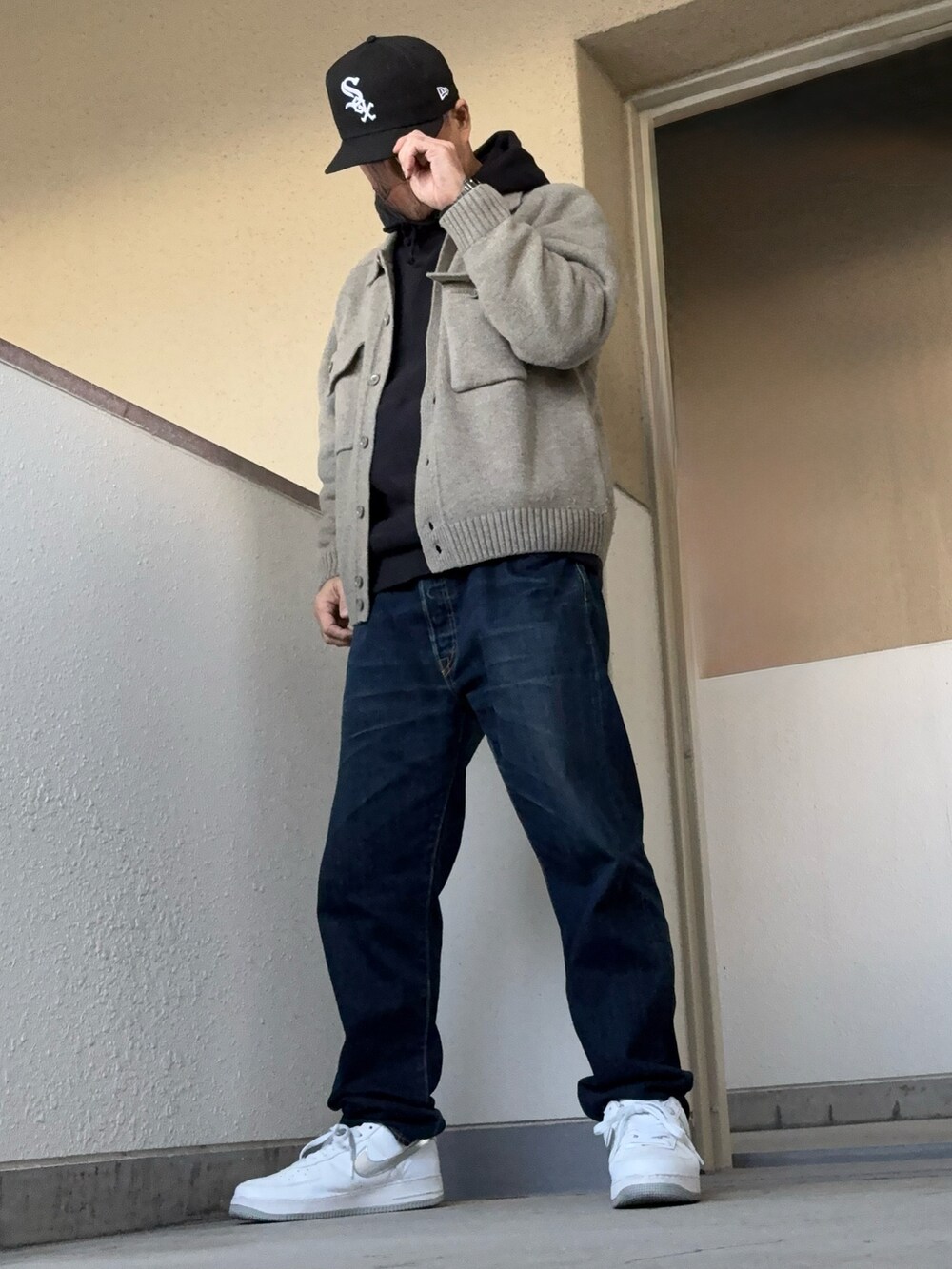グレー系のニット/セーター、ブラック系のパーカー、ブルー系のデニムパンツを着用したメンズの冬コーディネートの2枚目の写真