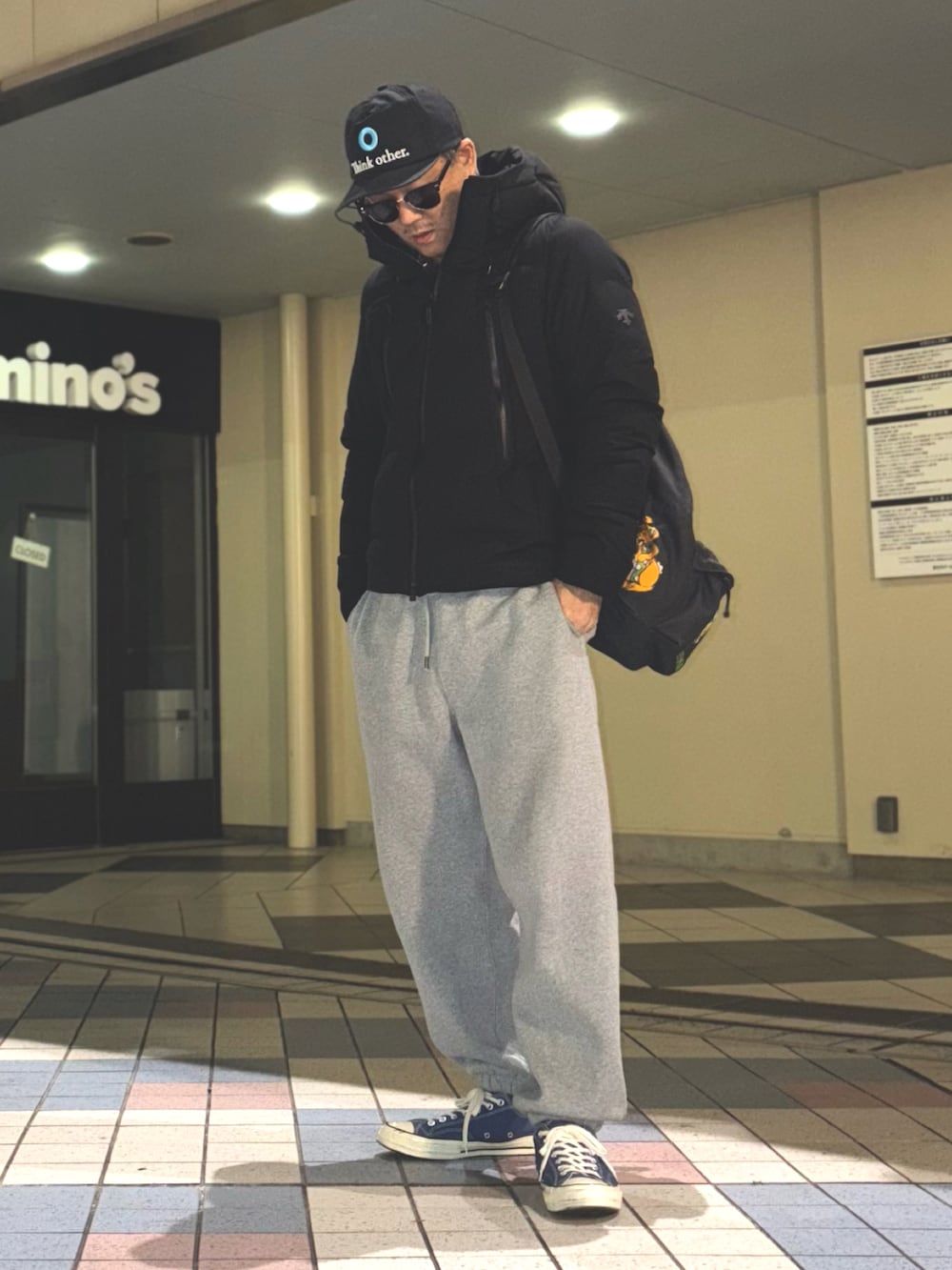 ブラック系のダウンジャケット/コート、ブルー系のスニーカー、ブラック系のバックパック/リュックを着用したメンズの冬コーディネートの2枚目の写真