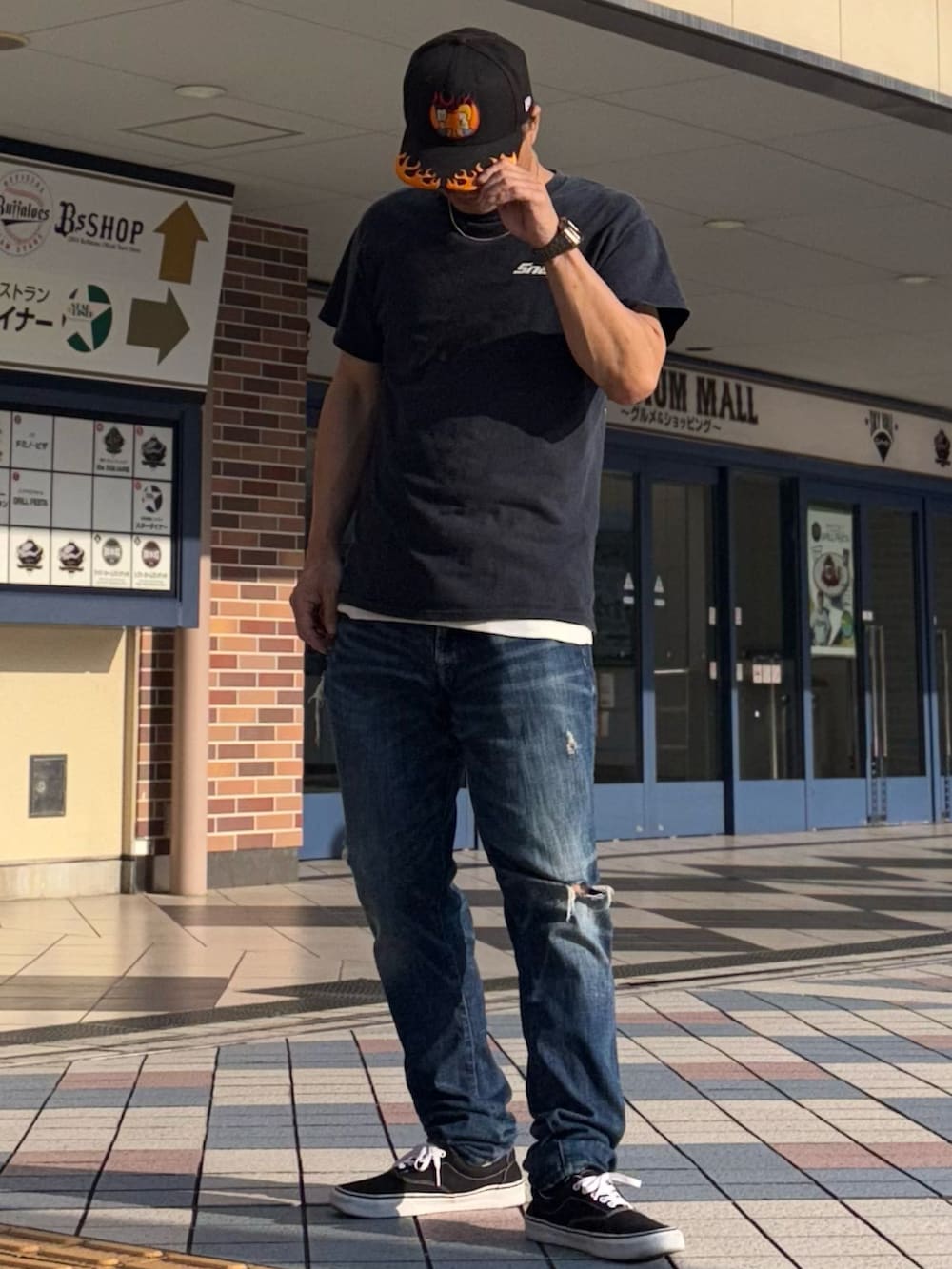 ブラック系のTシャツ/カットソー、ブルー系のデニムパンツ、ブラック系のスニーカーを着用したメンズの夏コーディネートの3枚目の写真