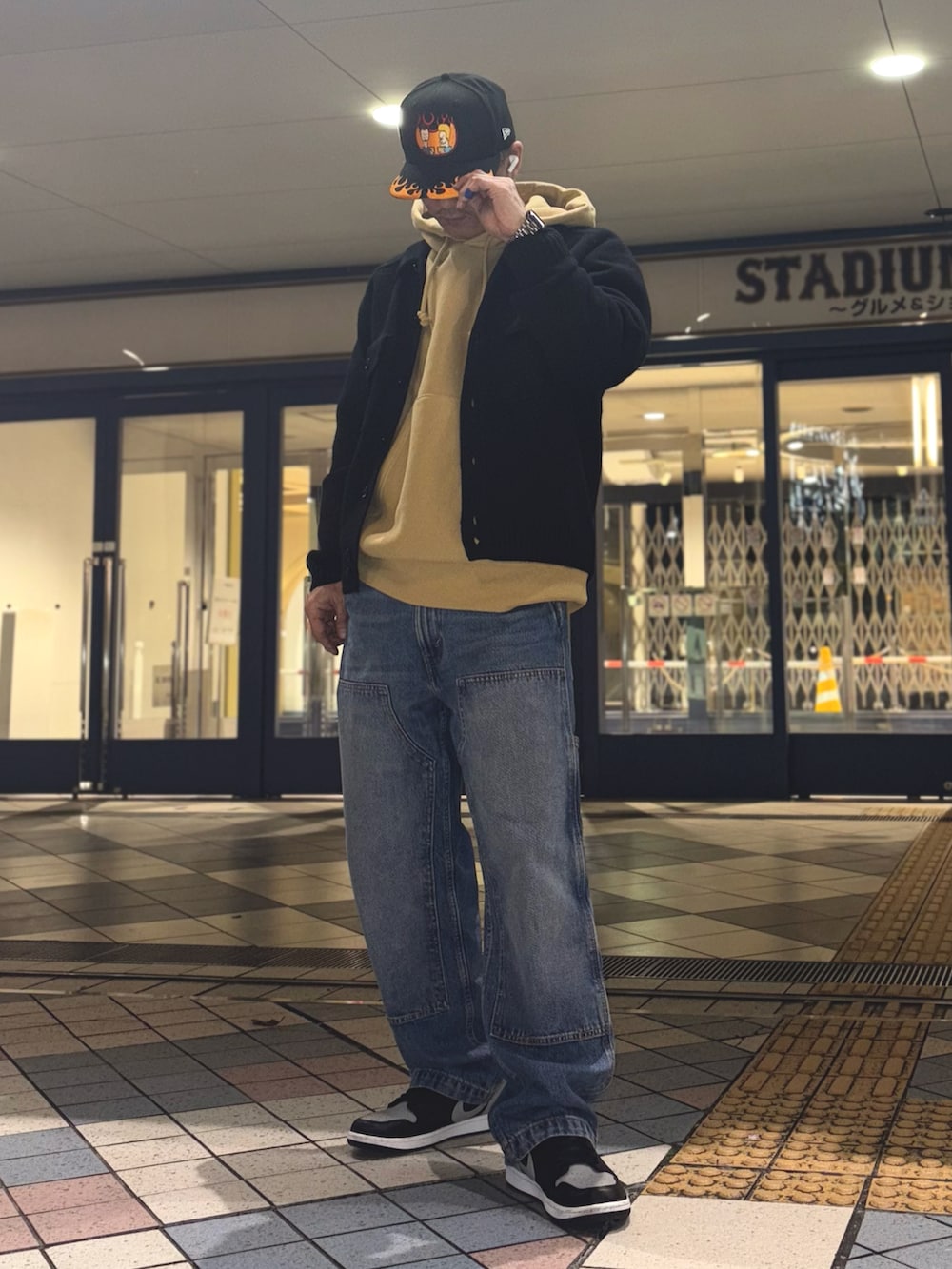 ブラック系のニット/セーター、イエロー系のパーカー、ブルー系のデニムパンツを着用したメンズの冬コーディネートの3枚目の写真