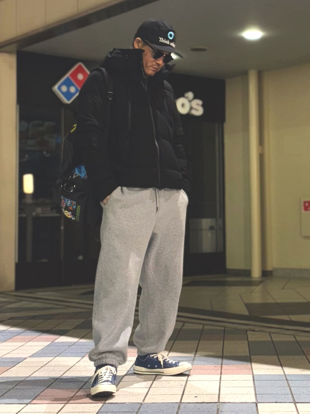 ブラック系のダウンジャケット/コート、ブルー系のスニーカー、ブラック系のバックパック/リュックを着用したメンズの冬コーディネートの3枚目の写真