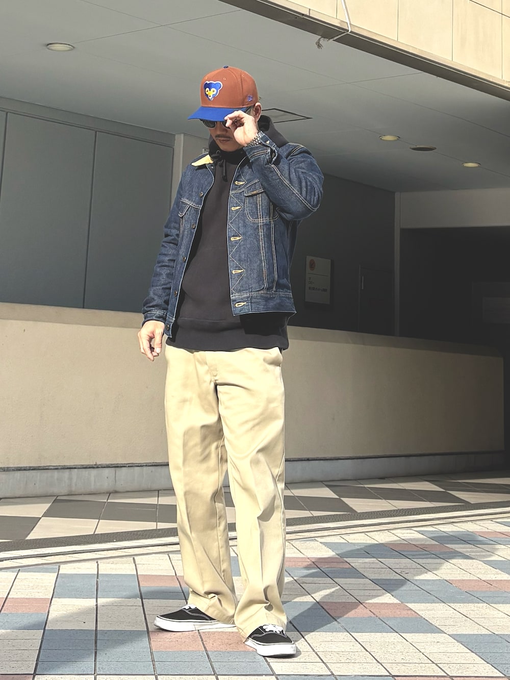 ブルー系のデニムジャケット、ブラック系のパーカー、ベージュ系のチノパンツを着用したメンズの冬コーディネートの2枚目の写真