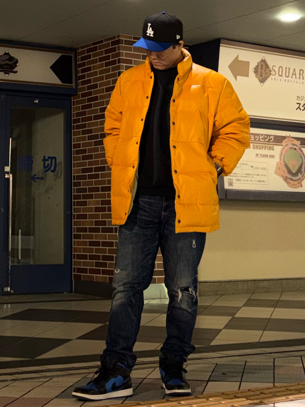 ブラック系のスウェット、イエロー系のダウンジャケット/コート、ブルー系のデニムパンツを着用したメンズの冬コーディネートの2枚目の写真