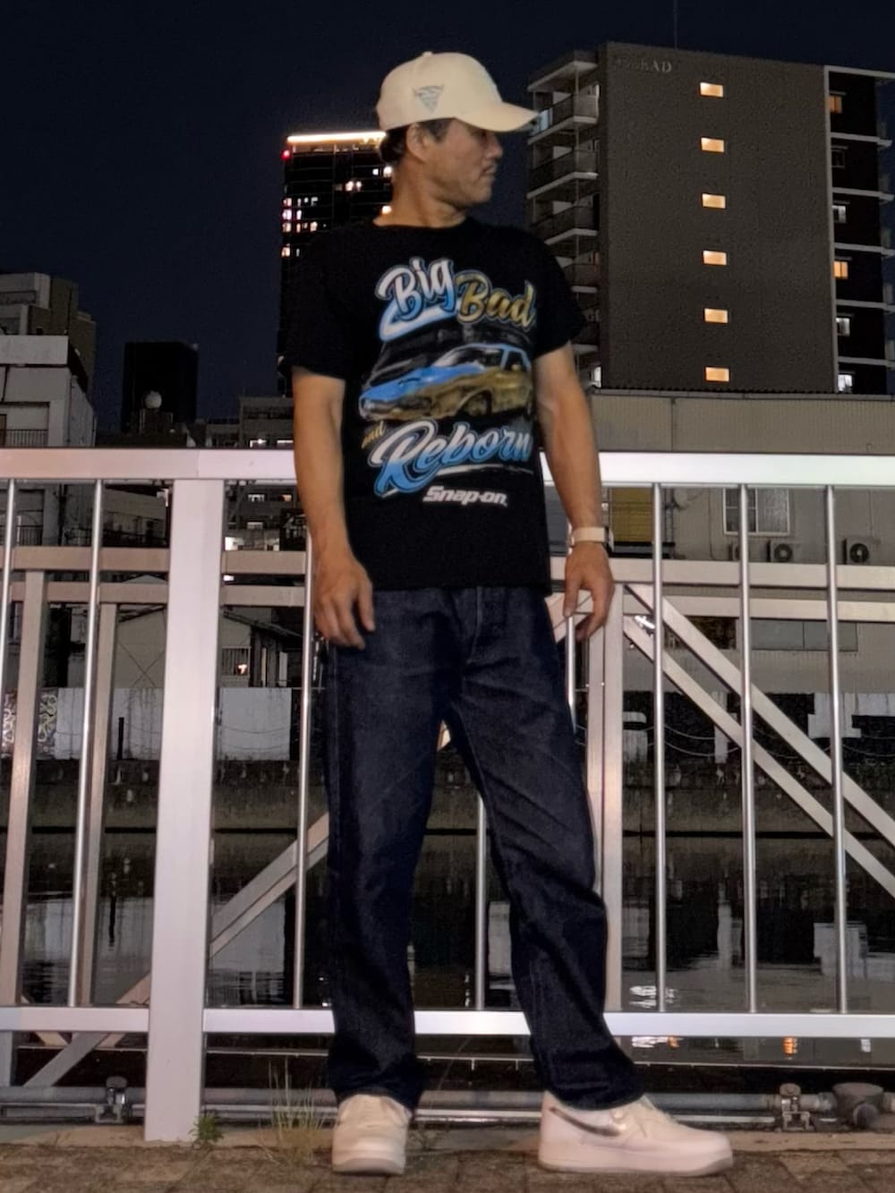 ブラック系のTシャツ/カットソー、ブルー系のデニムパンツ、シルバー系のスニーカーを着用したメンズの夏コーディネートの2枚目の写真