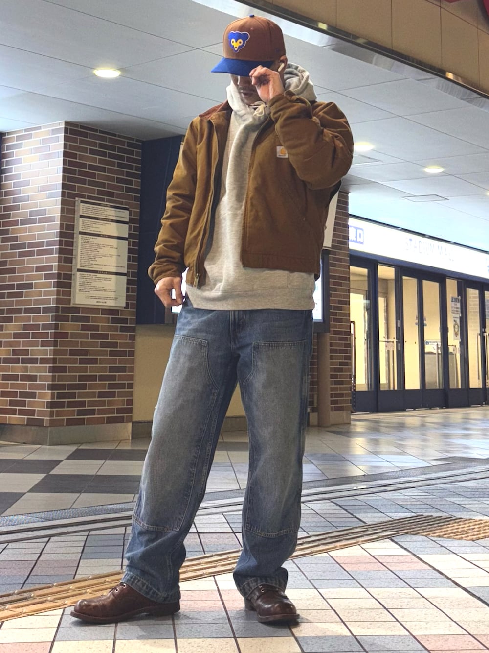 イエロー系のブルゾン、グレー系のパーカー、ブルー系のデニムパンツを着用したメンズの冬コーディネートの2枚目の写真