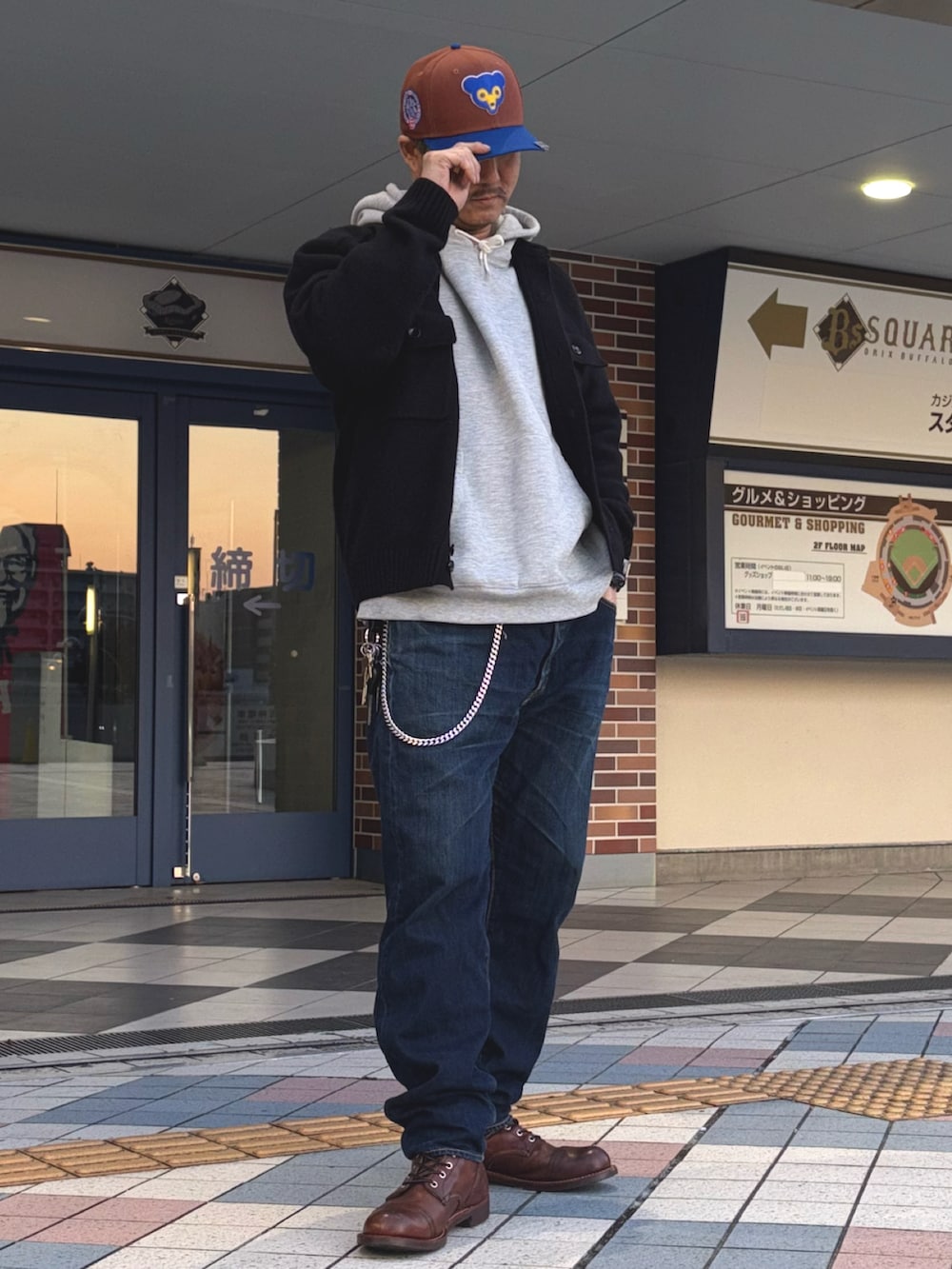 ブラック系のニット/セーター、グレー系のパーカー、ブルー系のデニムパンツを着用したメンズの春コーディネートの2枚目の写真