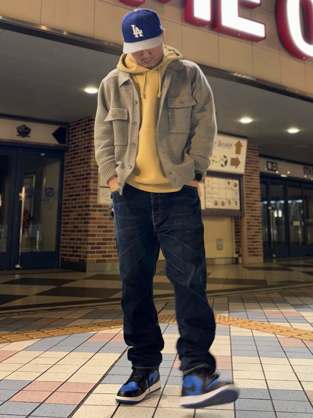 グレー系のニット/セーター、イエロー系のパーカー、ブルー系のデニムパンツを着用したメンズの春コーディネートの2枚目の写真
