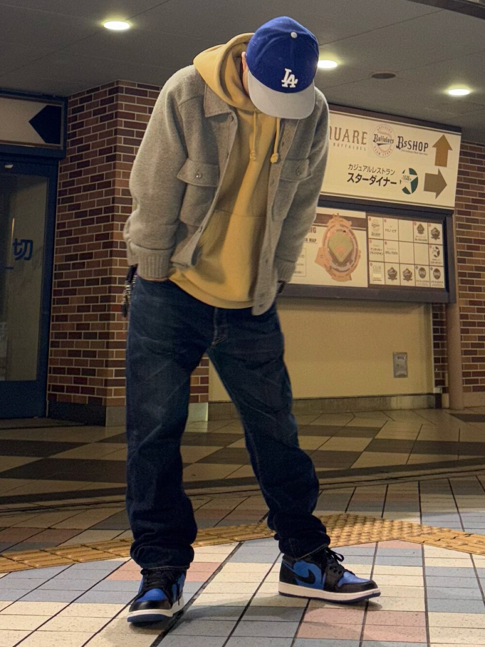 グレー系のニット/セーター、イエロー系のパーカー、ブルー系のデニムパンツを着用したメンズの春コーディネートの3枚目の写真