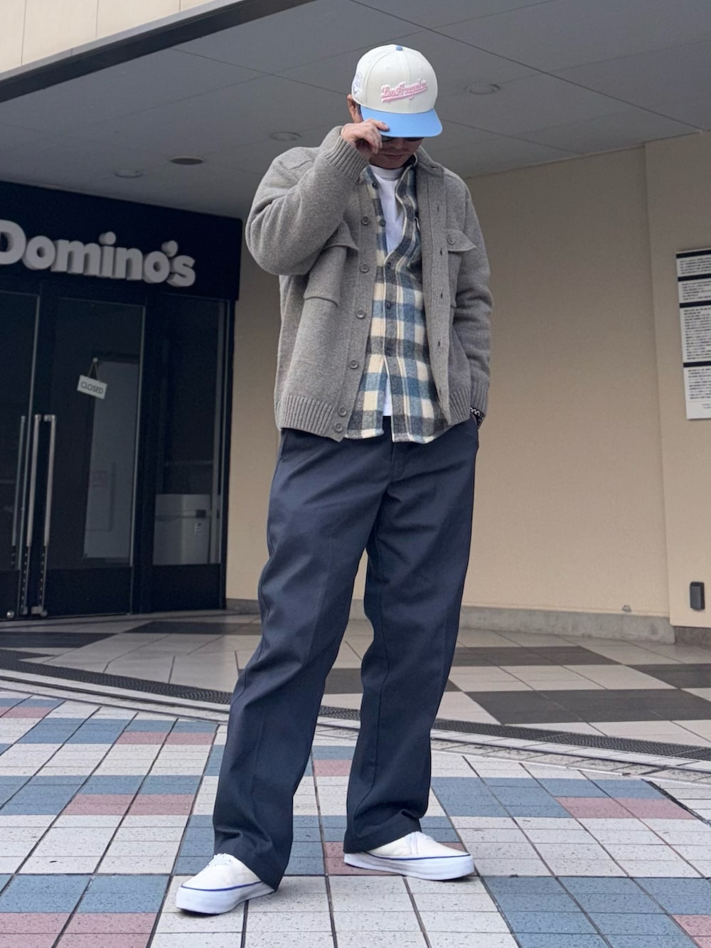 グレー系のニット/セーター、グレー系のチノパンツ、ホワイト系のスニーカーを着用したメンズの冬コーディネートの2枚目の写真