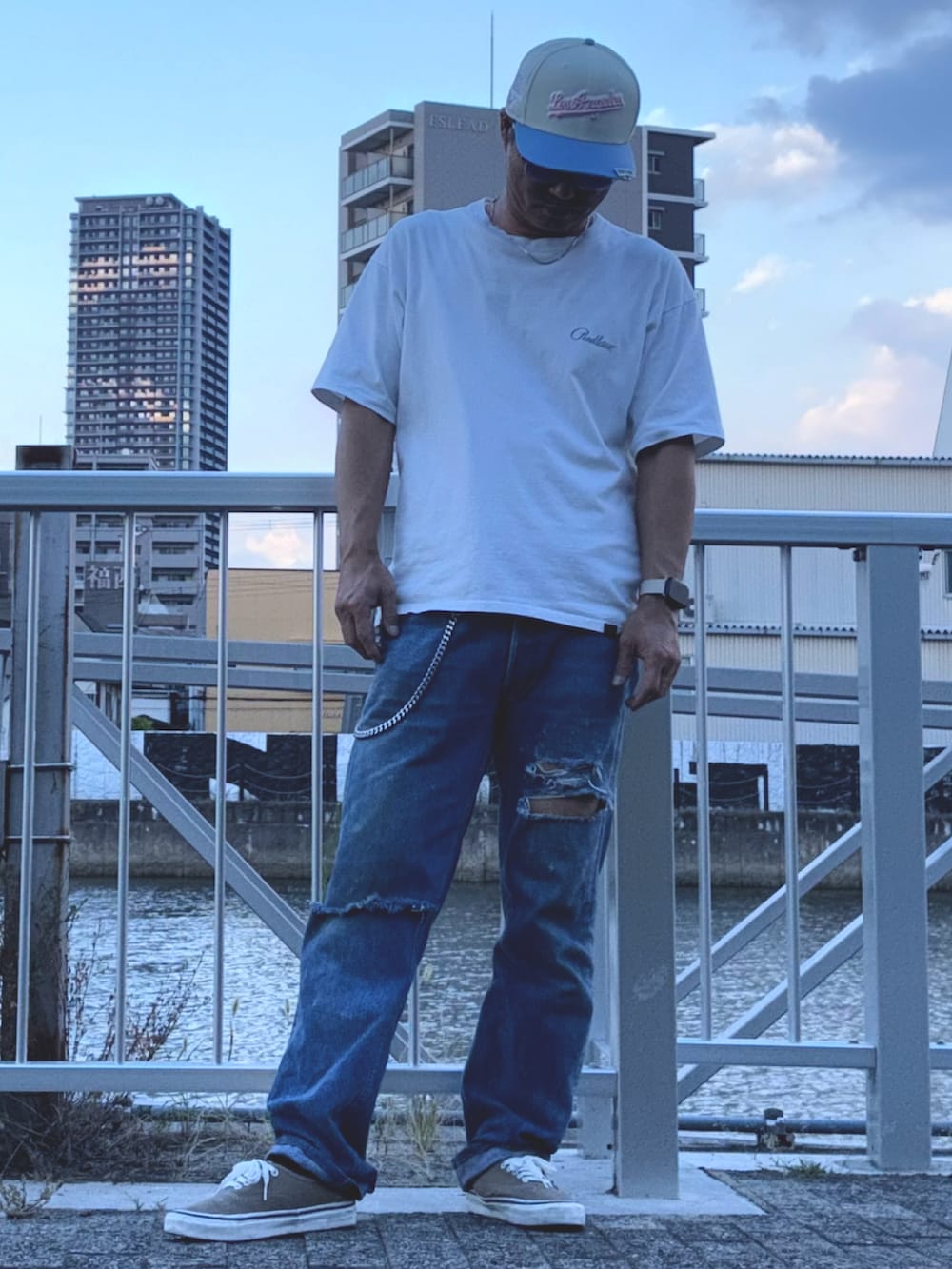 ホワイト系のTシャツ/カットソー、ブルー系のデニムパンツ、ベージュ系のスニーカーを着用したメンズの夏コーディネートの2枚目の写真