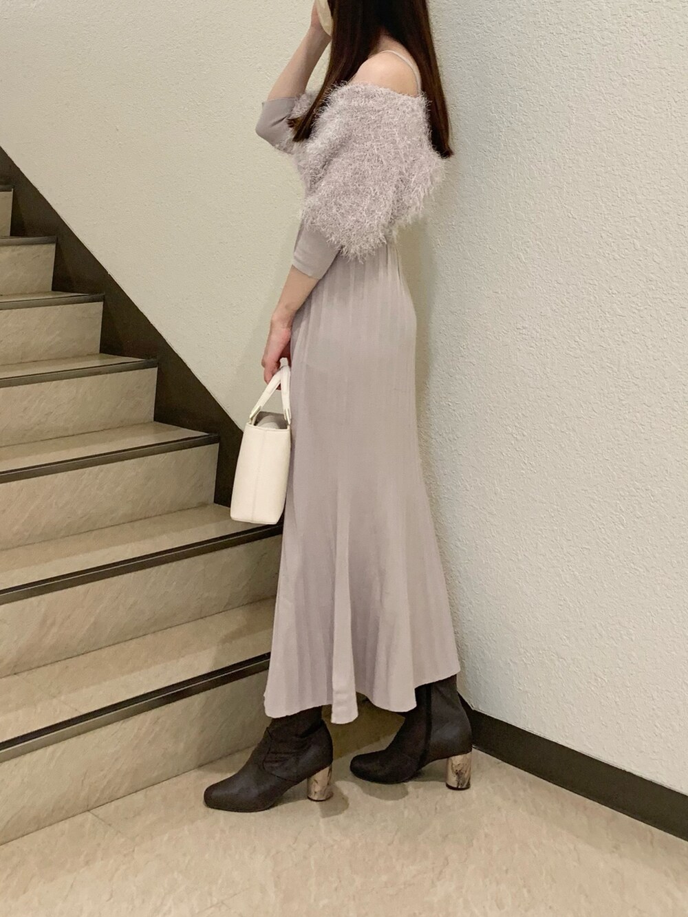 ベージュ系のワンピース、ホワイト系のハンドバッグ、ブラウン系のブーツを着用したレディースの冬コーディネートの2枚目の写真