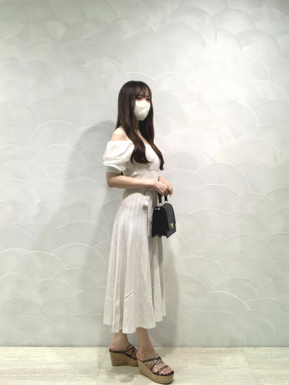 ブラック系のハンドバッグ、ホワイト系のワンピースを着用したレディースの夏コーディネートの2枚目の写真