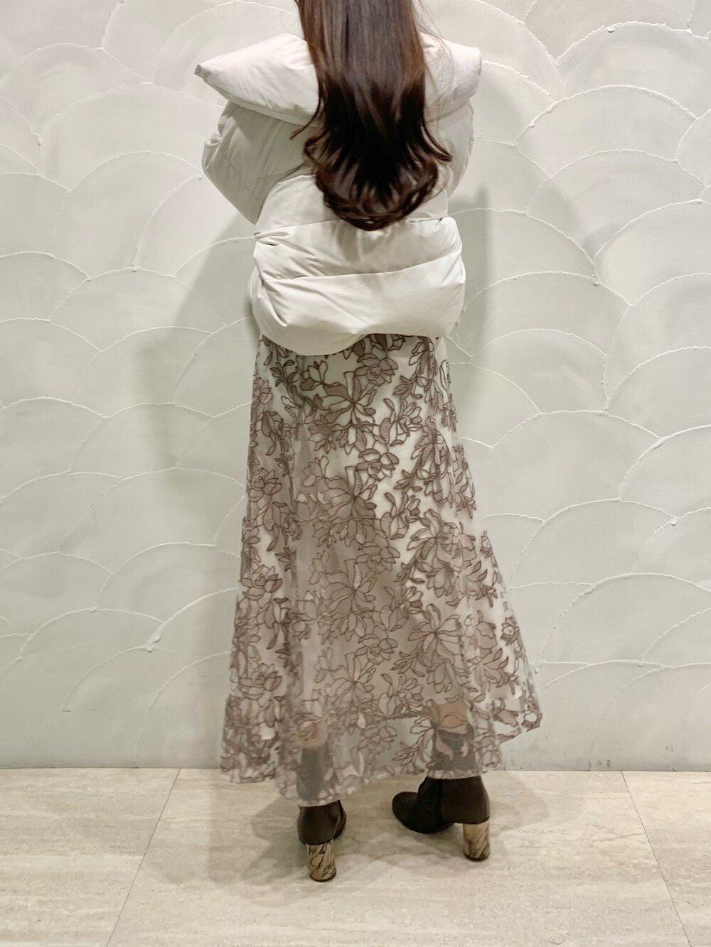 ピンク系のスカート、グレー系のニット/セーター、ホワイト系のダウンジャケット/コートを着用したレディースの秋コーディネートの3枚目の写真