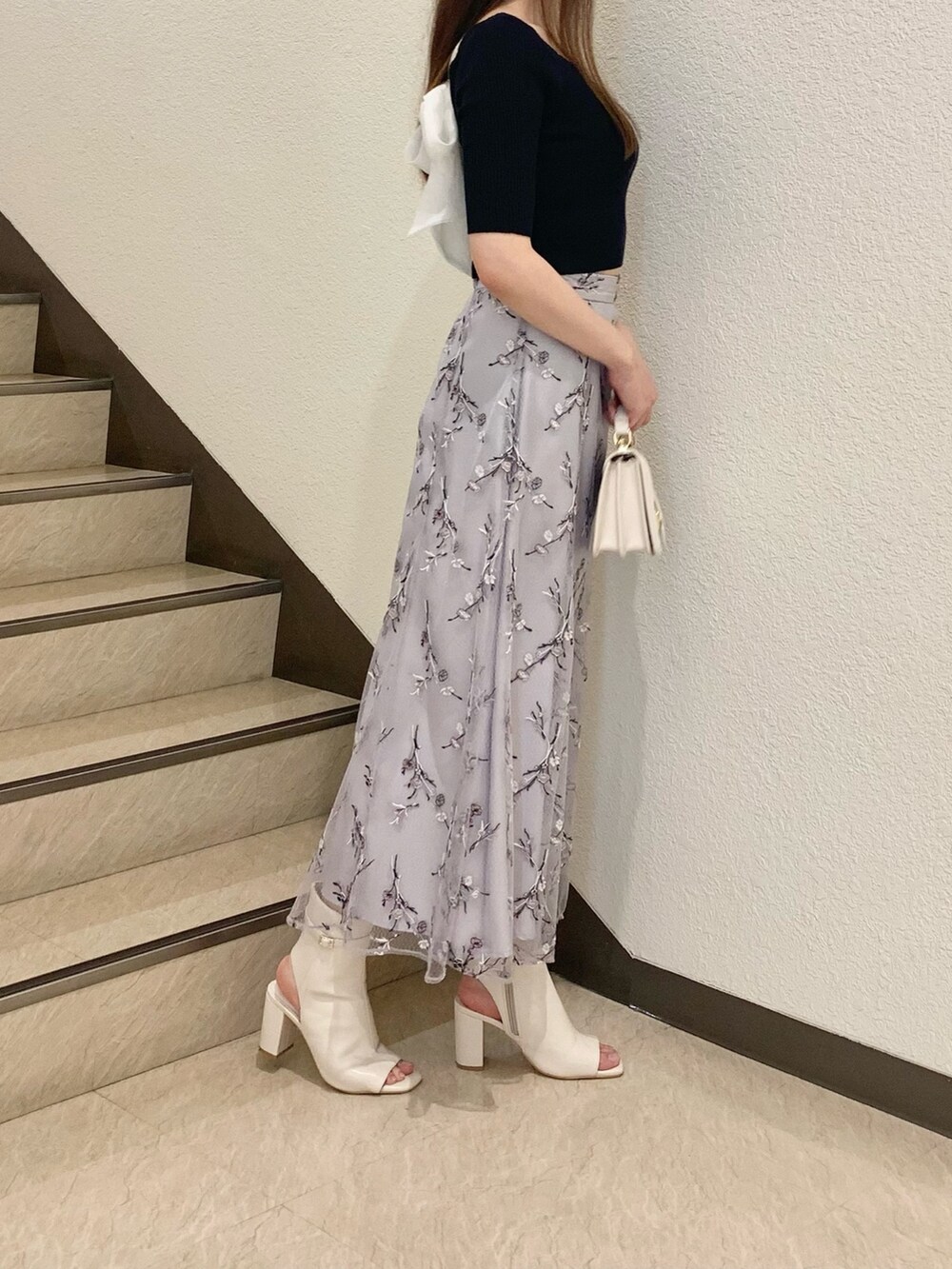 ホワイト系のハンドバッグ、ホワイト系のブーツ、パープル系のスカートを着用したレディースの春コーディネートの2枚目の写真