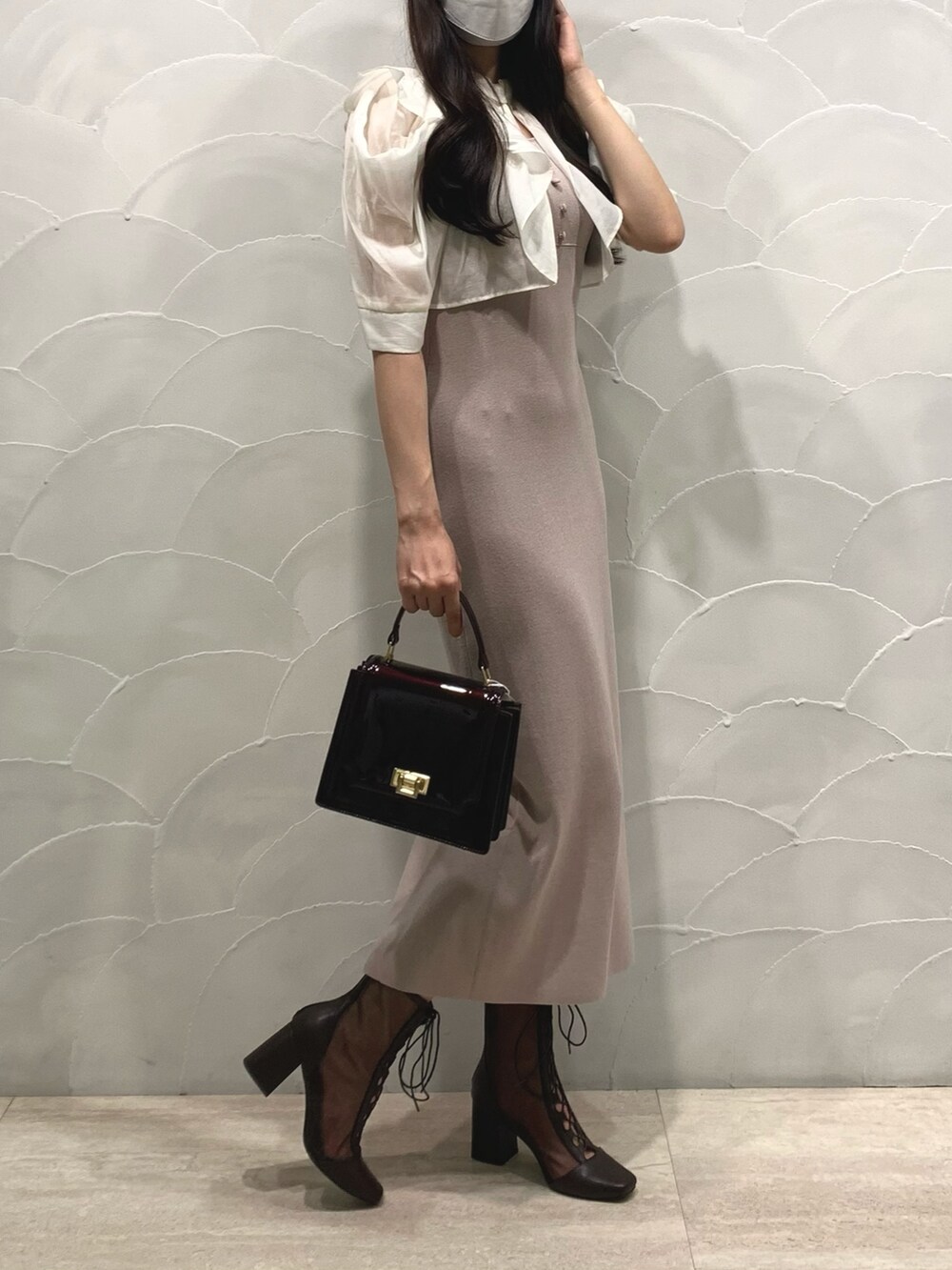 ブラウン系のハンドバッグ、ベージュ系のワンピース、ブラウン系のブーツを着用したレディースの夏コーディネートの2枚目の写真
