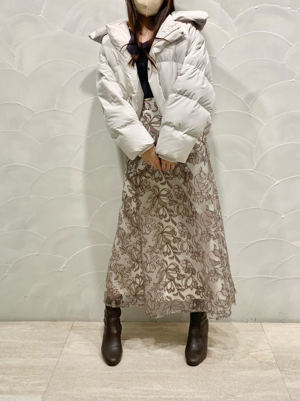 ピンク系のスカート、グレー系のニット/セーター、ホワイト系のダウンジャケット/コートを着用したレディースの秋コーディネートの2枚目の写真