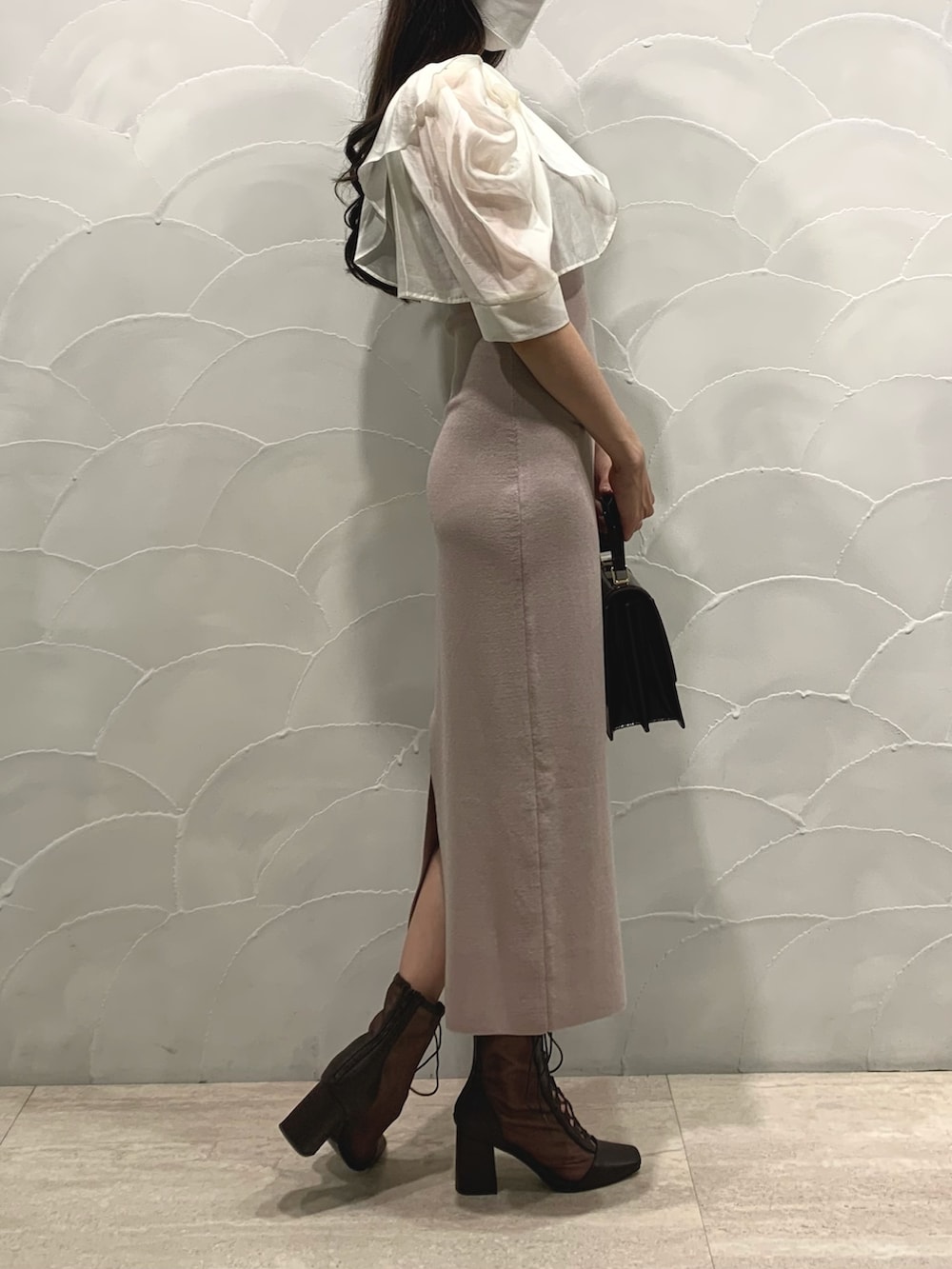 ブラウン系のハンドバッグ、ベージュ系のワンピース、ブラウン系のブーツを着用したレディースの夏コーディネートの3枚目の写真