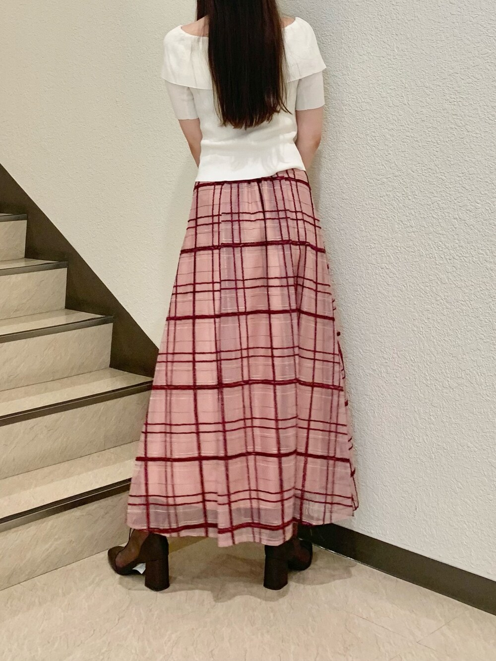 ピンク系のスカート、ホワイト系のニット/セーター、ブラウン系のブーツを着用したレディースの夏コーディネートの2枚目の写真