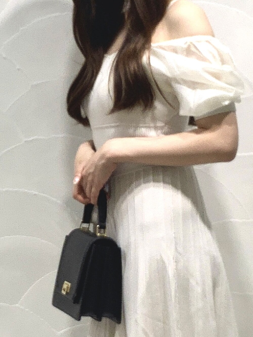 ブラック系のハンドバッグ、ホワイト系のワンピースを着用したレディースの夏コーディネートの4枚目の写真