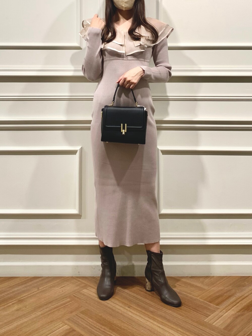 ブラック系のハンドバッグ、ブラウン系のブーツ、ピンク系のワンピースを着用したレディースの冬コーディネートの2枚目の写真